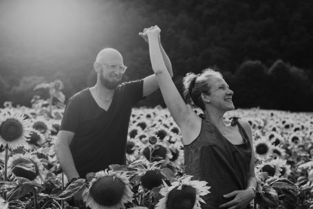 Ein Paar in einem Sonnenblumenfeld, glücklich und Hand in Hand.